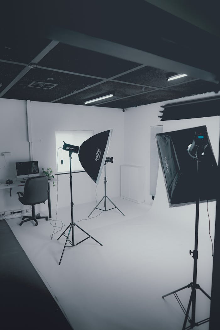 A clean, modern photography studio with lighting equipment and white backdrop.