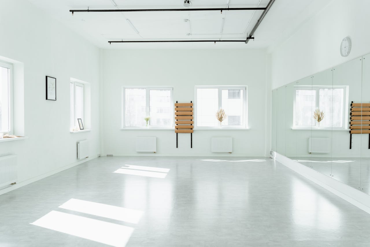 Bright and empty dance studio with mirrors and sunlight streaming in.