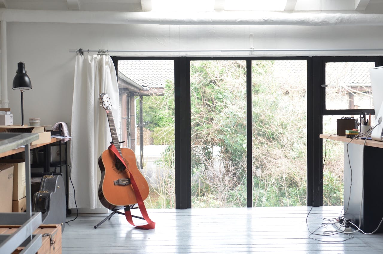 Interior of room with big glass doors tables and guitar on floor stand